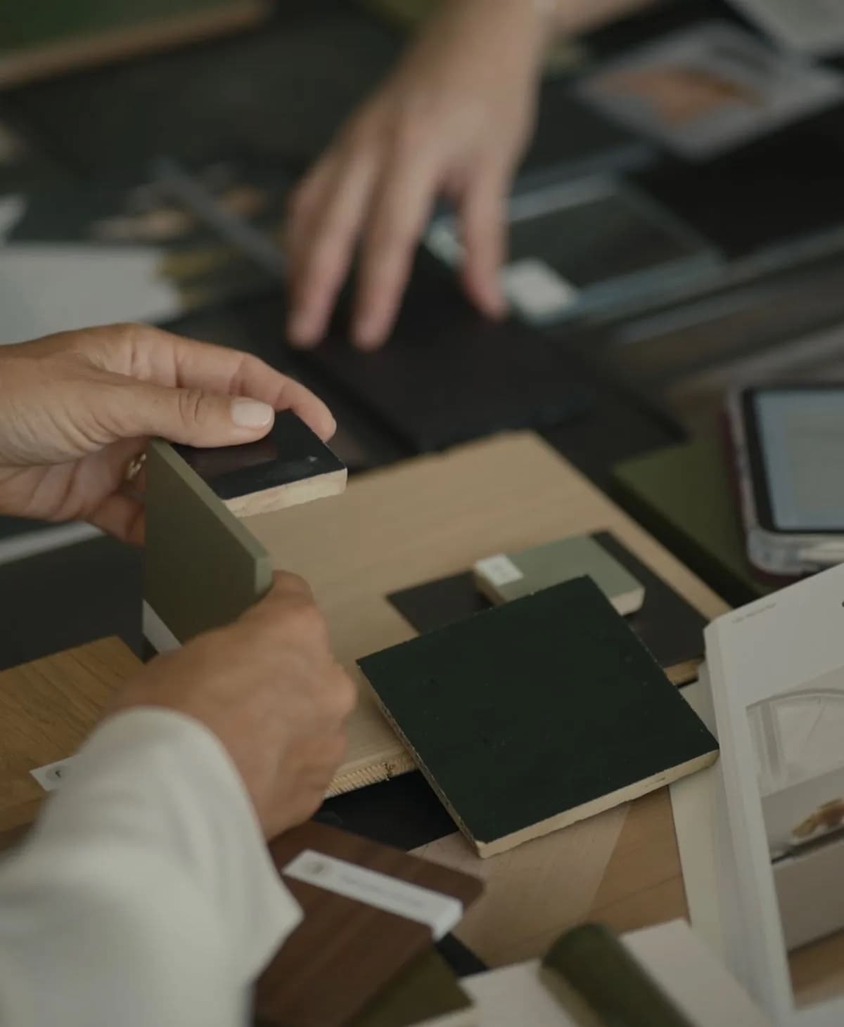 Hands arranging material samples on a desk