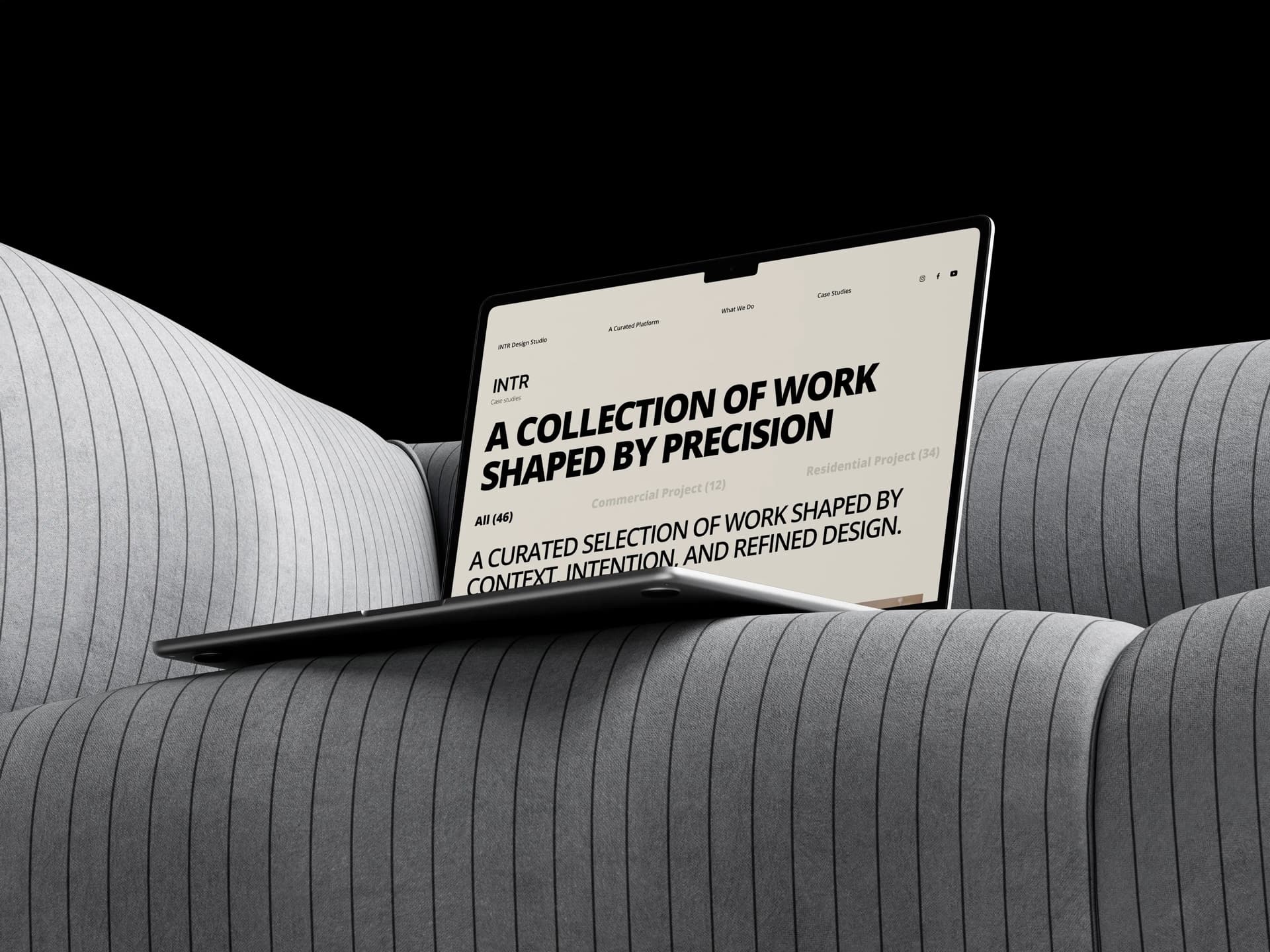 Laptop on a ribbed grey sofa showing A Collection of Work Shaped by Precision